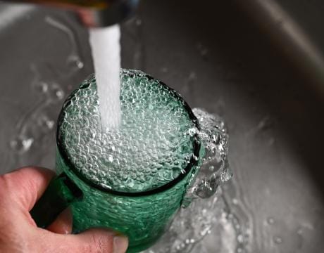 A glass of water being filled from a tap.